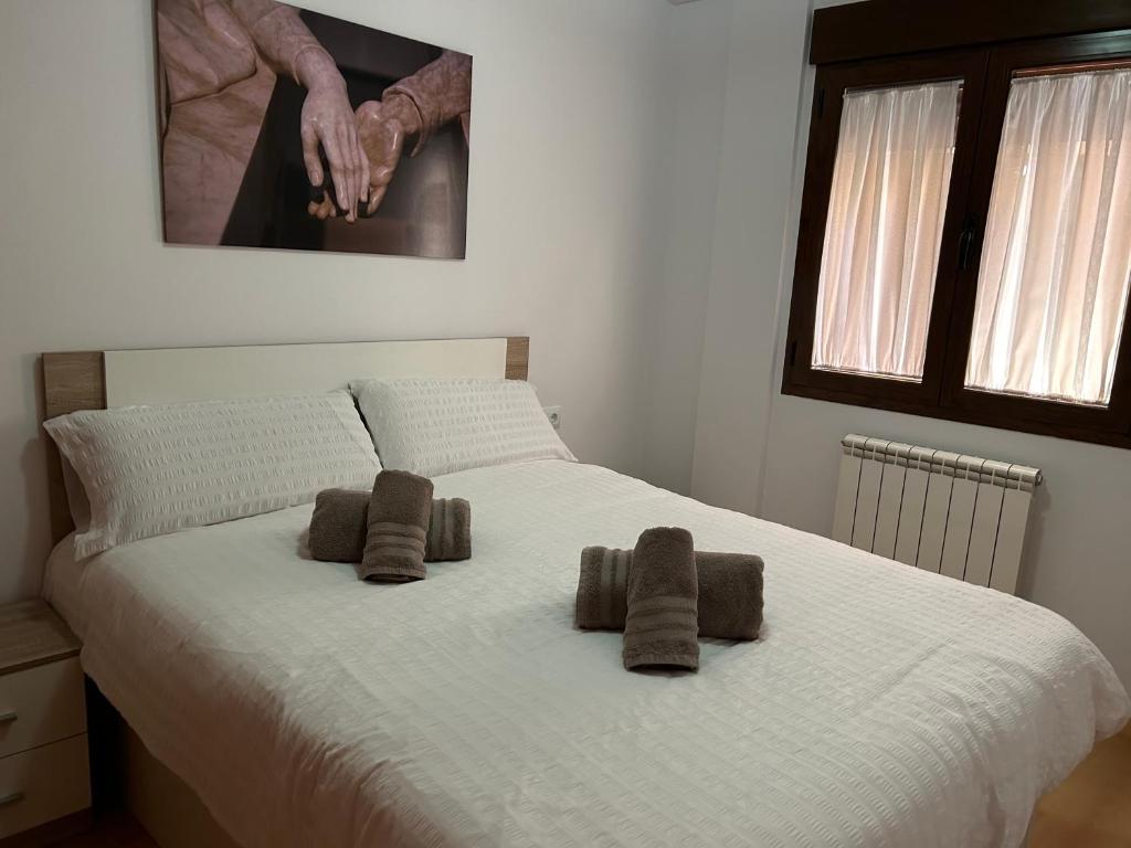 a bedroom with a white bed with two brown towels on it at alojamientosteruelmarqueses La Marquesita in Teruel