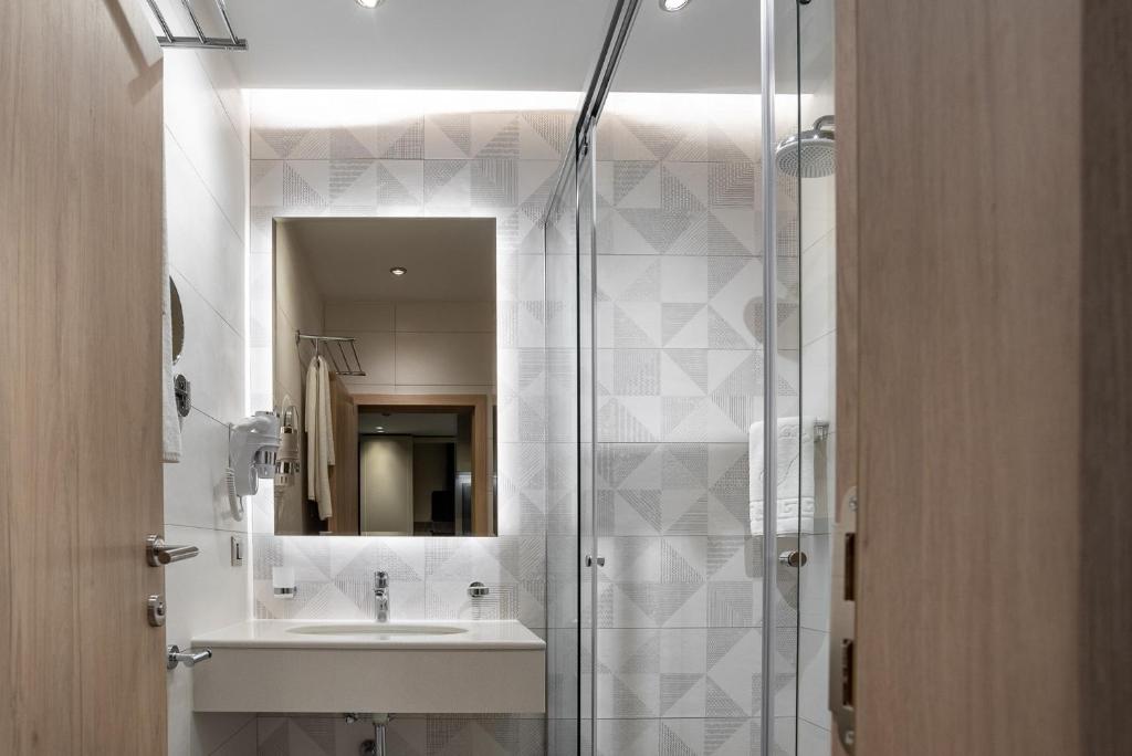 een badkamer met een wastafel en een douche bij City Park Inn Apartment Verona in Plovdiv