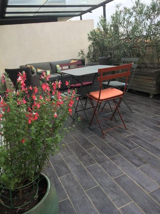 - une terrasse avec une table, des chaises et des fleurs dans l'établissement Appartement T3 à 2mn de la Plage, à LʼÎle-Rousse