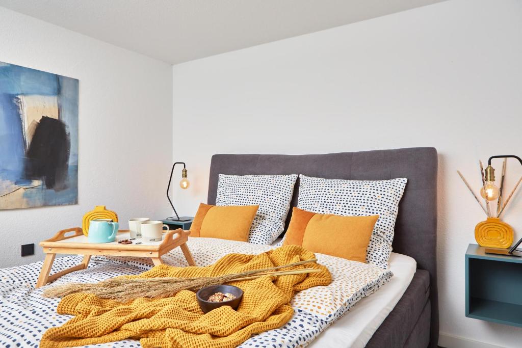 um quarto com uma cama com almofadas laranja e uma mesa em Nord29 - Exklusive Ferienwohnung am Waldrand Meschede em Meschede