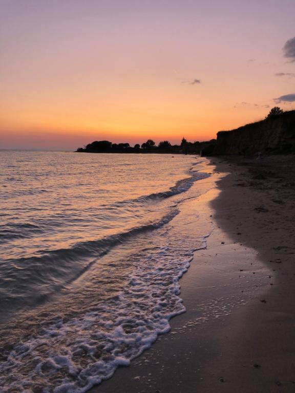 een zonsondergang op het strand met de kustlijn bij Apartments Villa Prima in Privlaka