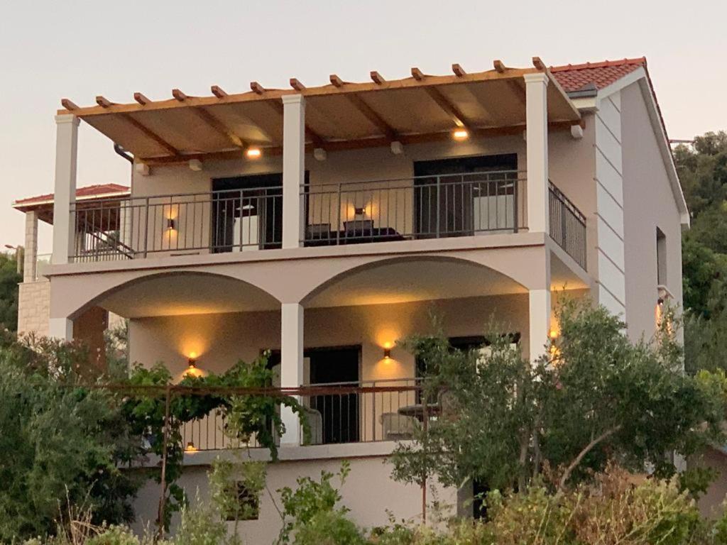 a large white building with lights on the balcony at Apartman Vitanov in Vinišće