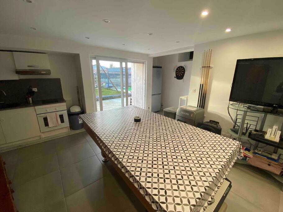 een woonkamer met een tafel en een televisie bij Appartement individuel au rdc d’une maison in Le Péage-de-Roussillon