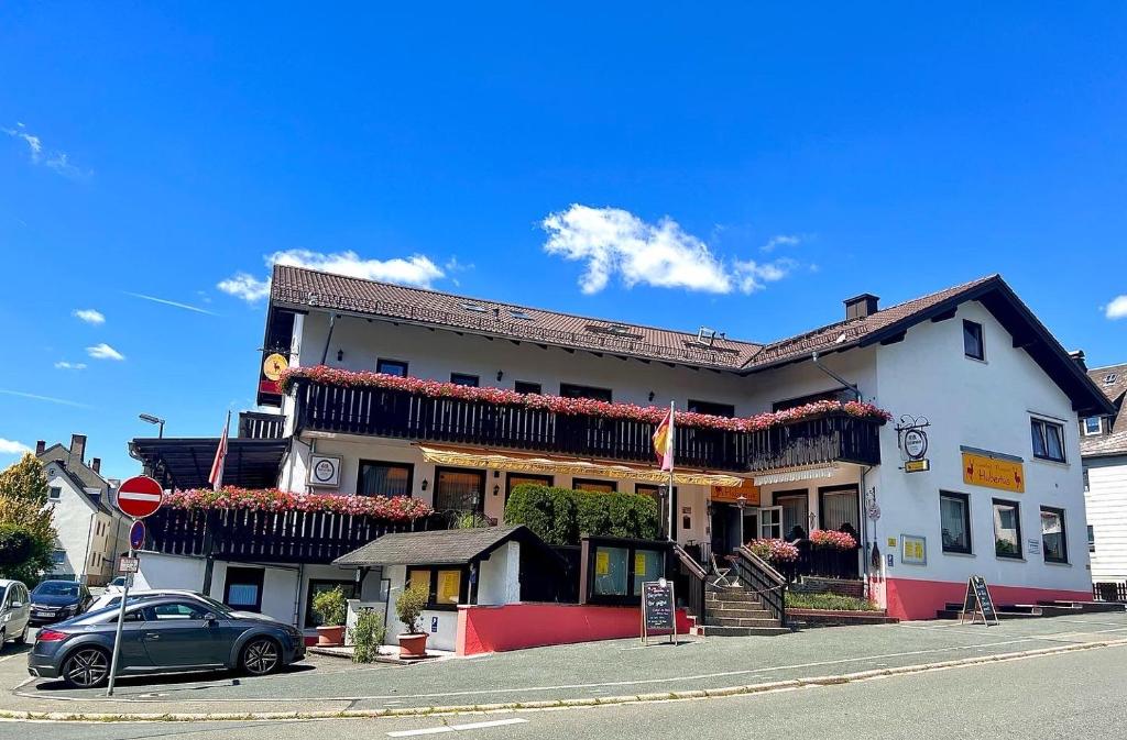 un grand bâtiment blanc au coin d'une rue dans l'établissement Pension Hubertus, à Bad Steben