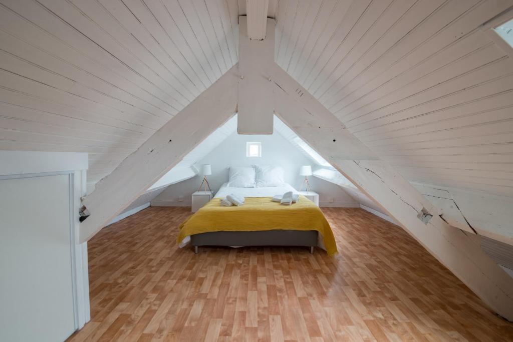 a bedroom with a yellow bed in a attic at AR PENNITI - Magnifique maison en pierre proche plage in Landéda