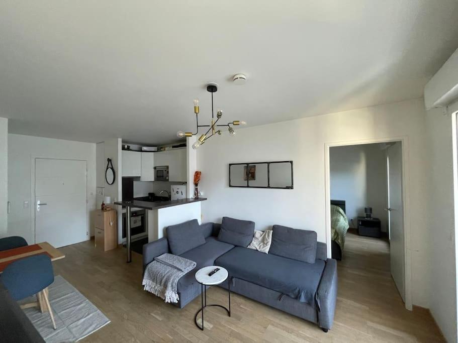 een woonkamer met een blauwe bank en een tafel bij Luxury & Cosy apart with balcony Eiffel Tower view in Issy-les-Moulineaux