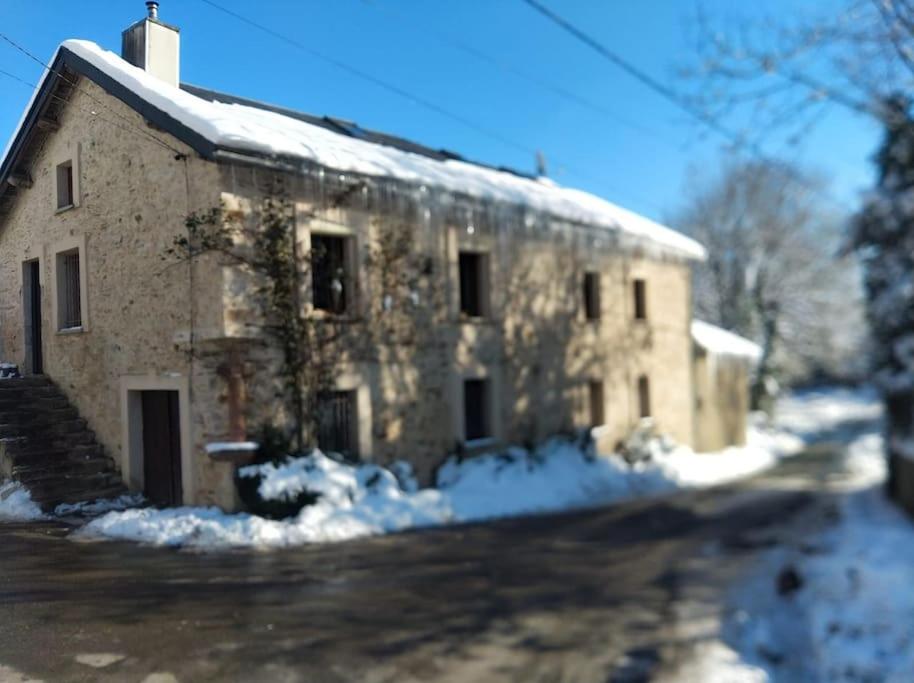- un grand bâtiment en pierre avec de la neige dans l'établissement Maison de campagne, à Moulin-Mage