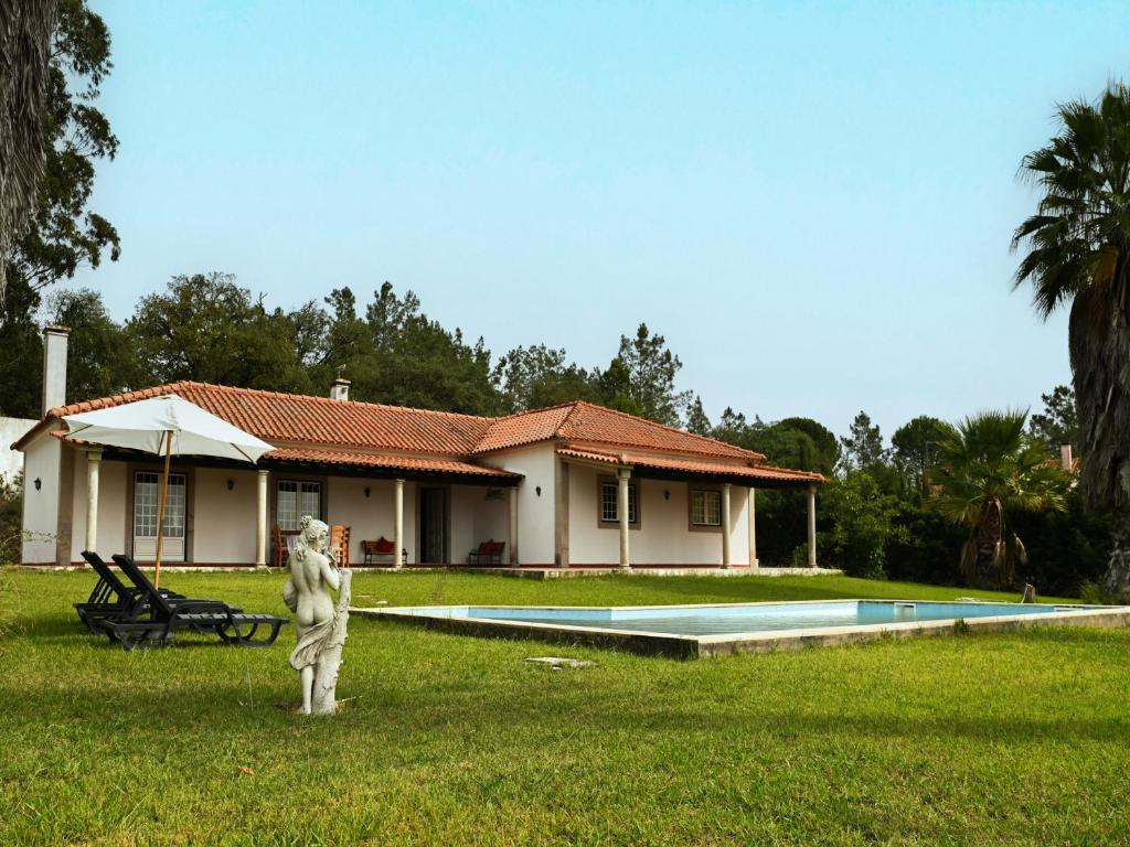 une maison avec une piscine et une statue dans la cour dans l'établissement Fantástica Casa de Campo com Piscina perto de Lisboa, à Santarém