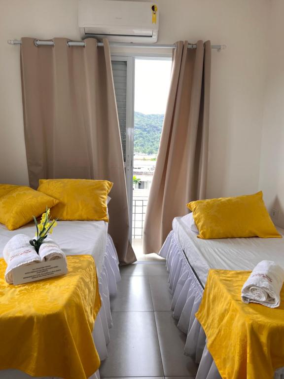 um quarto com duas camas com lençóis amarelos e uma janela em Pousada Suites Enseada Guaruja no Guarujá