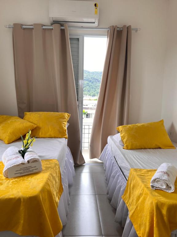 a room with two beds with yellow sheets and a window at Pousada Suites Enseada Guaruja in Guarujá