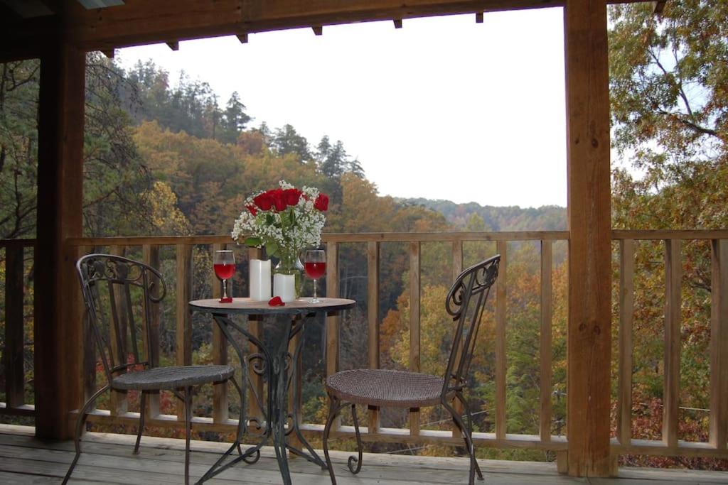 a table with two chairs and a vase of flowers on a porch at Little Cabin All To Yourself in Sevierville