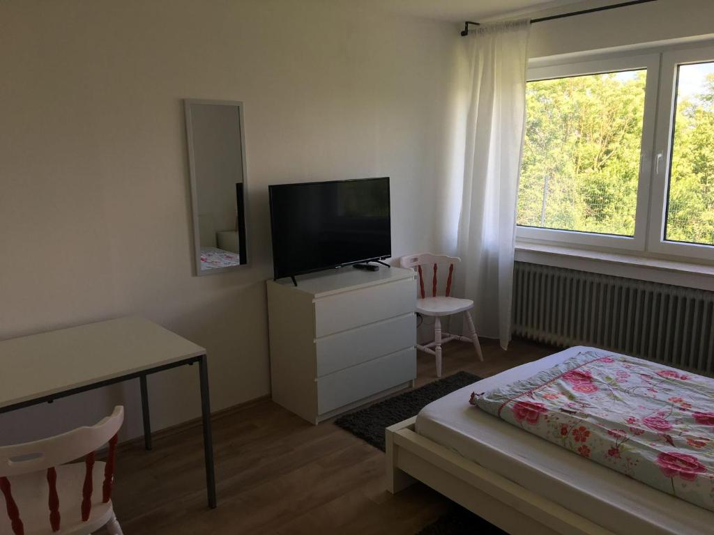 a bedroom with a television and a desk and a bed at Mayen, Im Möhren, Privatzimmer Nr1, Waldrand, nähe Nürburgring & Burg Eltz, Gemeinschaftsbad in Mayen