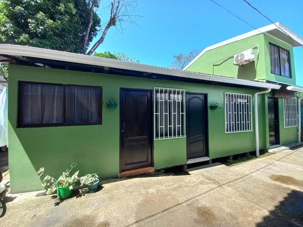 a green house with black doors and windows at Apartamentos Caimán Tortuguero in Tortuguero
