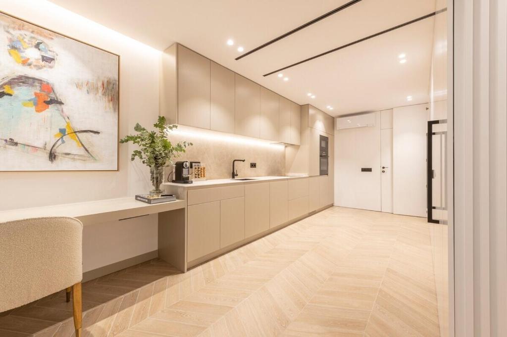 a kitchen with white cabinets and a painting on the wall at MyHouseSpain - Luminoso piso en Chamberí in Madrid