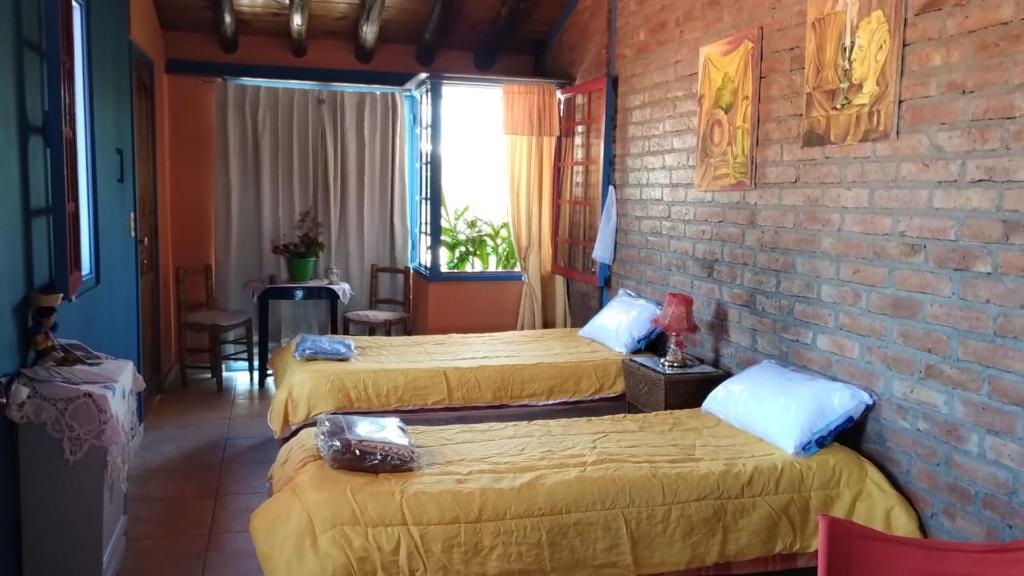 a room with three beds and a brick wall at Departamento Pura Luz con cochera opcional in Gobernador Benegas