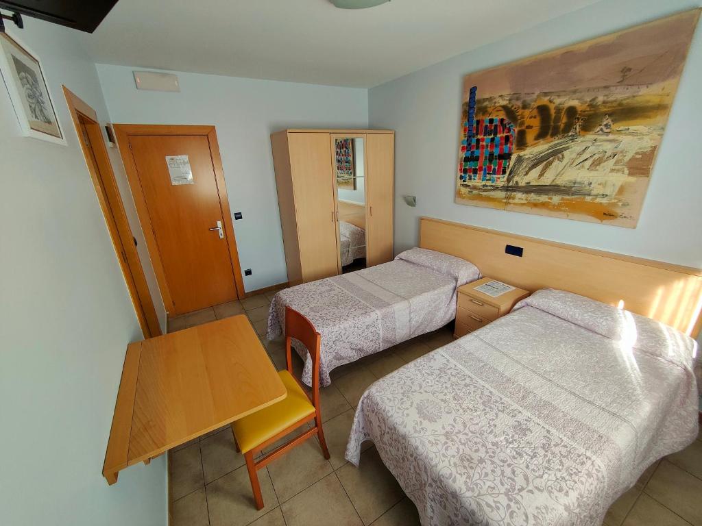 Habitación de hotel con 2 camas y mesa en Hostería Sol en San Miguel de Meruelo