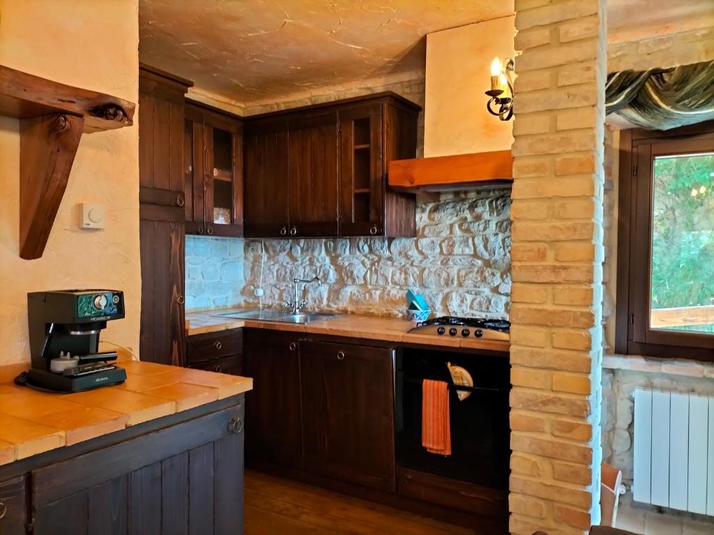 kuchnia z drewnianymi szafkami i piekarnikiem w obiekcie Old House w mieście Penna San Giovanni