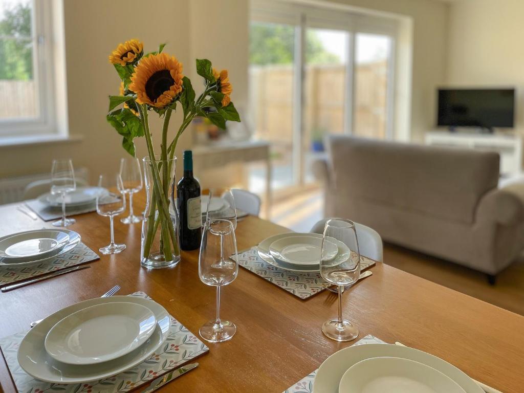 uma mesa com pratos e óculos e um vaso com girassóis em Bay Tree House em Dove Holes