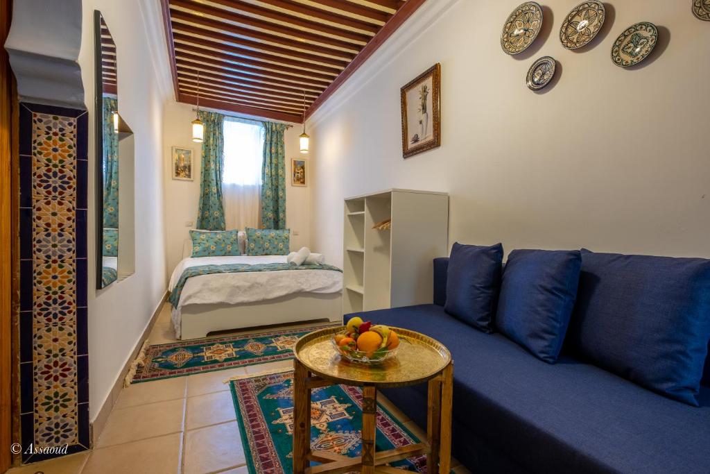 uma sala de estar com um sofá azul e uma mesa em Riad Bin Souaki em Chefchaouen