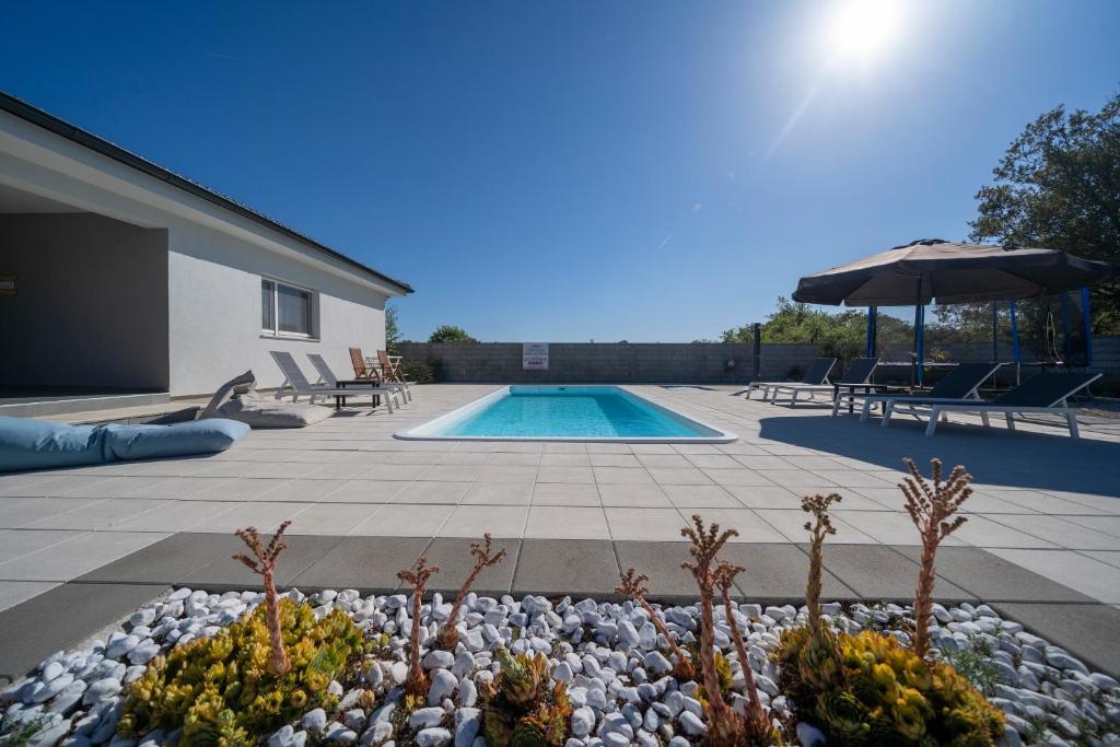 a backyard with a swimming pool with rocks and an umbrella at Villa Dreams in Briševo