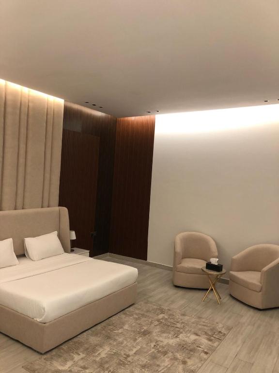 sypialnia z białym łóżkiem i 2 krzesłami w obiekcie شاليهات بالي ان الفندقية w mieście Dżudda
