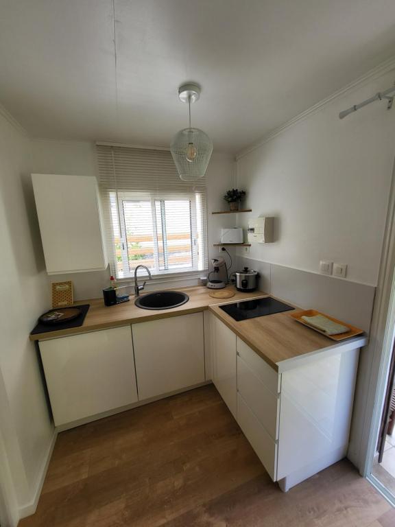 a kitchen with white cabinets and a sink and a window at Ô Vert-Tige : Piscine Jardin Pétanque Proche centre ville in Entre-Deux