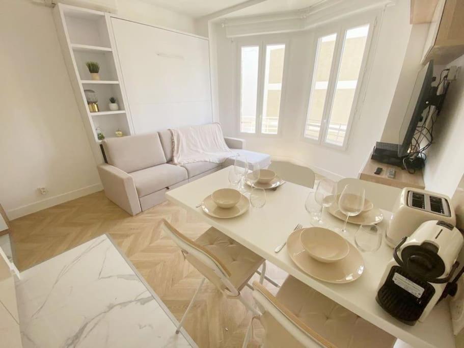 sala de estar blanca con mesa y sofá en Appartement 2P Idéalement Placé Juan les Pins en Juan-les-Pins