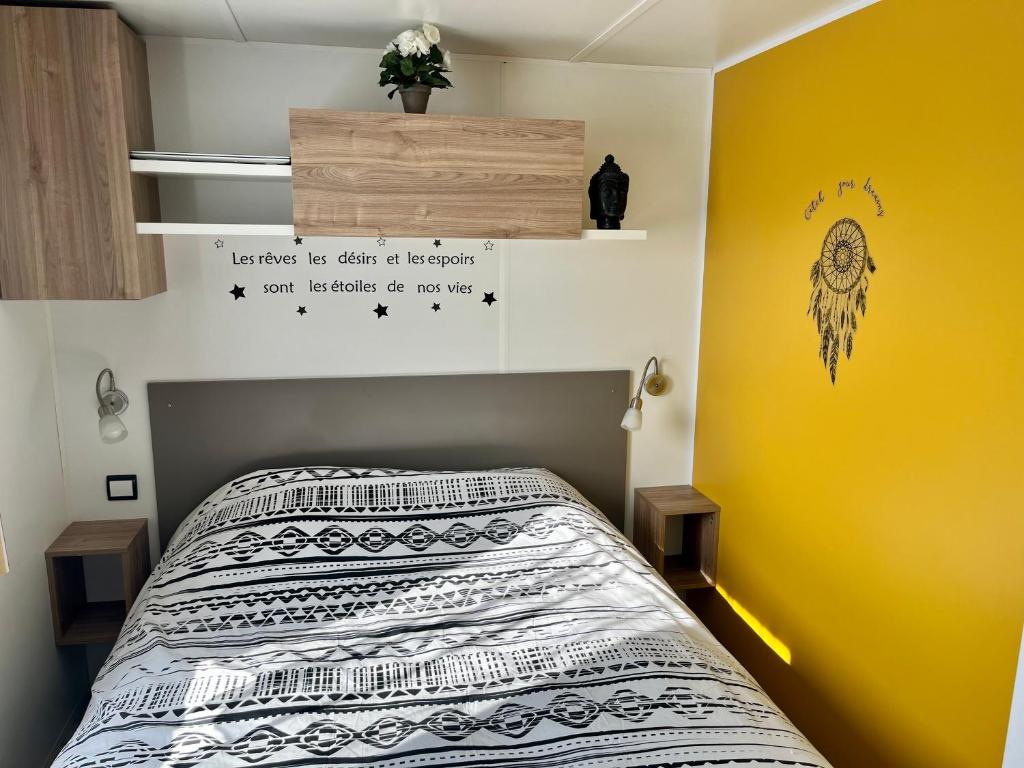 - une chambre avec un lit et un mur jaune dans l'établissement Mobile home Zen Siblu Fréjus, à Fréjus