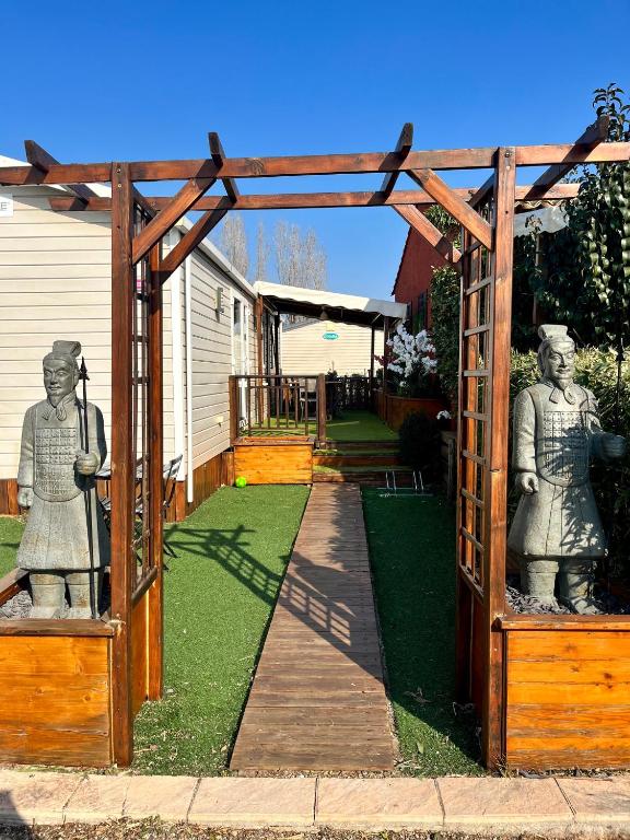 une arche en bois avec deux statues dans une cour dans l'établissement Mobile home Zen Siblu Fréjus, à Fréjus
