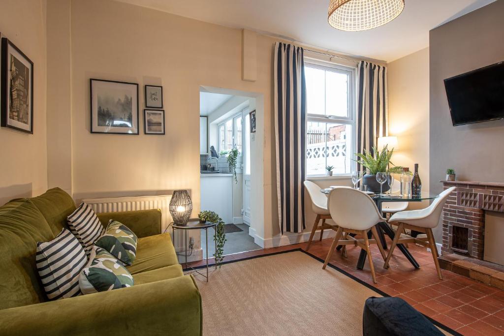 a living room with a green couch and a table at 3 bedroom home sleeps 5 close to Chester City Centre welcomes couples, small groups, families and contractors in Chester