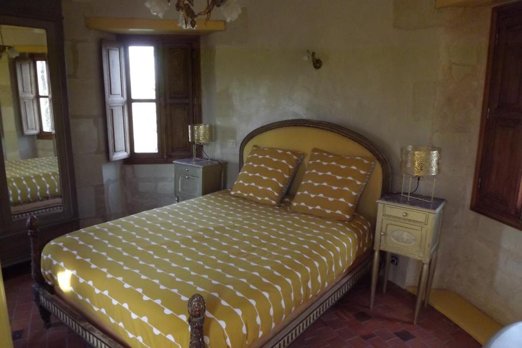 1 dormitorio con 1 cama, 2 mesas y espejo en Chambres d'hôtes La Tour de Bellevue en Saumur