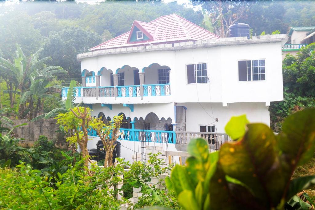 a white house with a blue balcony at Robin Hood Guest House in Port Antonio