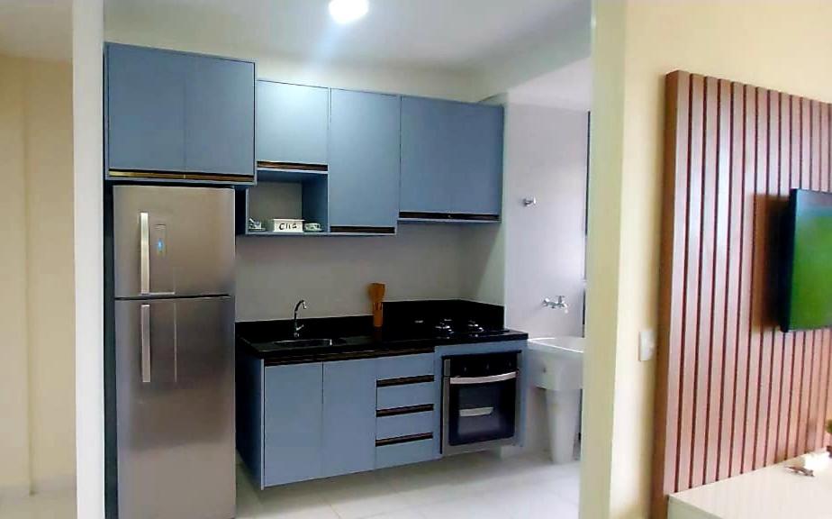 cocina con armarios azules y nevera de acero inoxidable en Apartamento clube próximo à praia, en Caraguatatuba