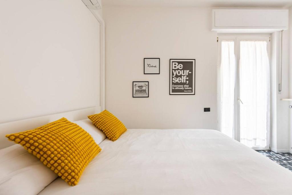 een witte slaapkamer met gele kussens op een bed bij Maison Teodoro in Verona