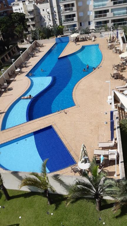 an overhead view of a large swimming pool with chairs and palm trees at Condomínio Resort Top - Apartamento novo! in Guarujá