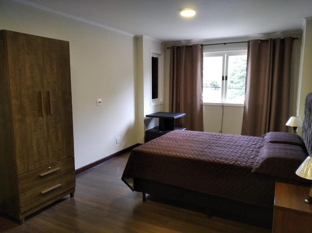 een slaapkamer met een bed, een dressoir en een raam bij Suíte dprata in Campos do Jordão