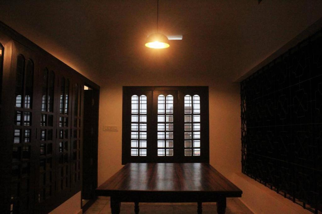 a room with a wooden table and two windows at RIO CASA , Private villa in soochipara in Meppādi