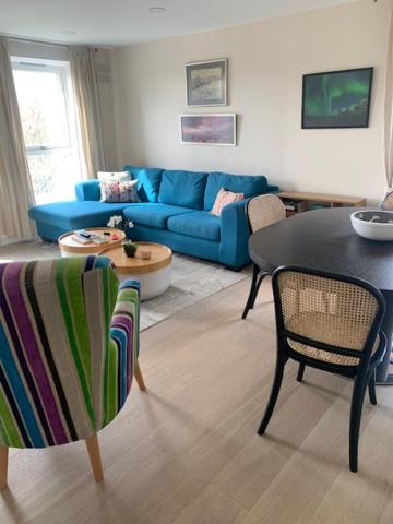 sala de estar con sofá azul, mesa y sillas en 2 Bedroom Chelsea Apartment en Londres
