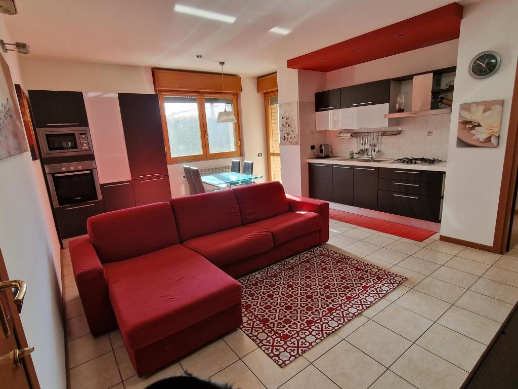 a living room with a red couch and a kitchen at Appartamento Volta in Rho