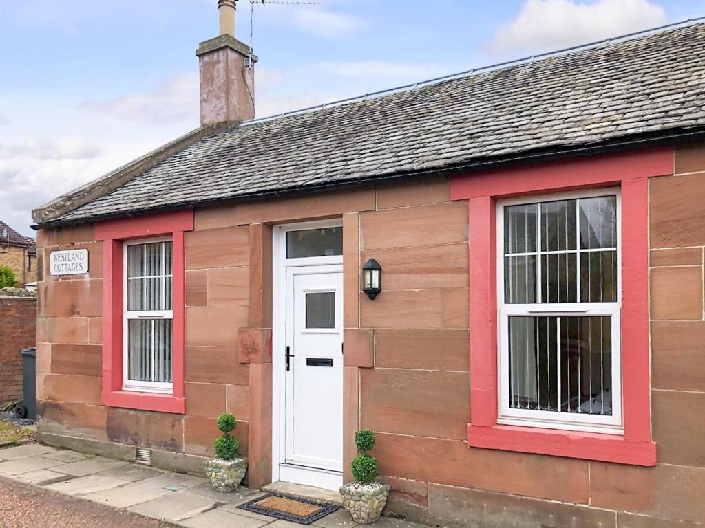 una piccola casa con una porta bianca e finiture rosse di City Cottage a Liberton