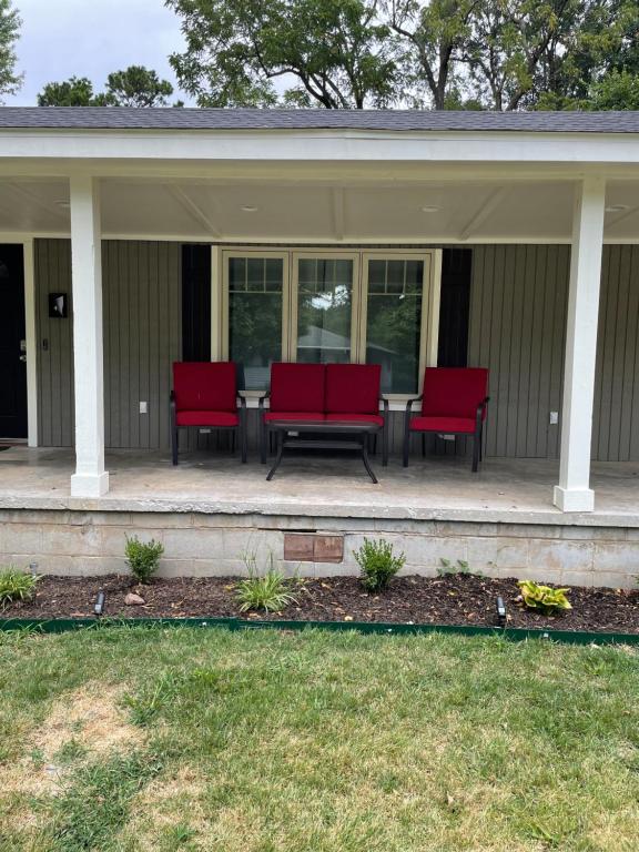 een veranda met rode stoelen en een tafel. bij Beautiful Home Fully Equipped, Sleeps 8! in Springdale