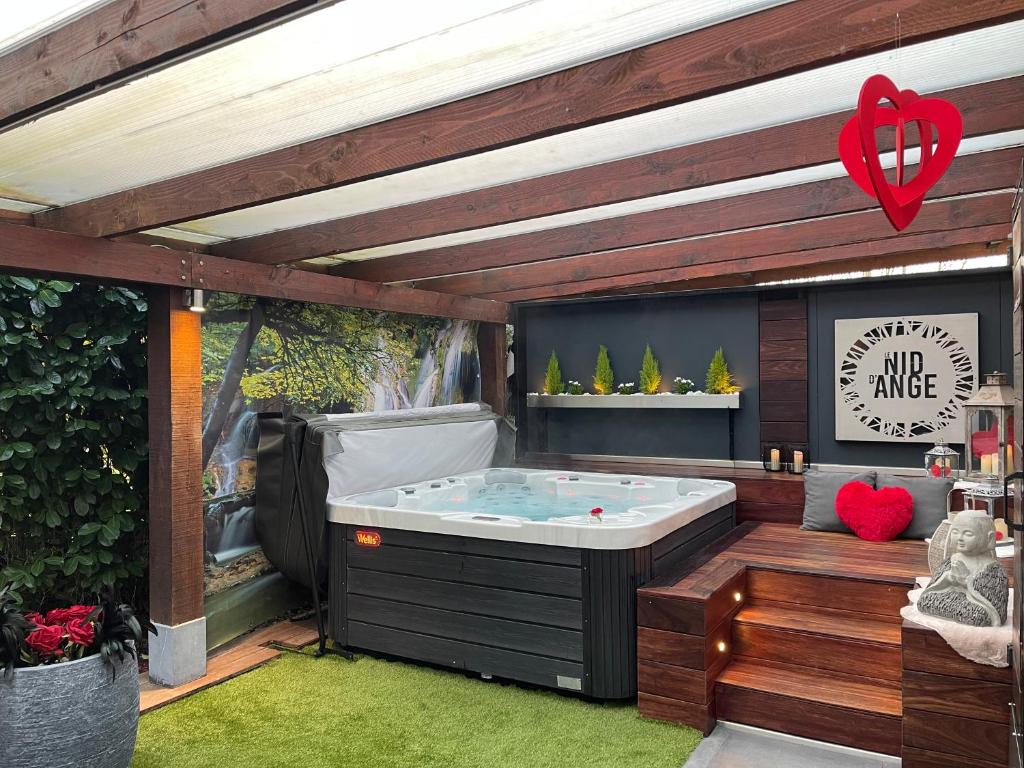 een jacuzzi in een achtertuin met een houten terras bij Le Nid d'Ange in Ohey