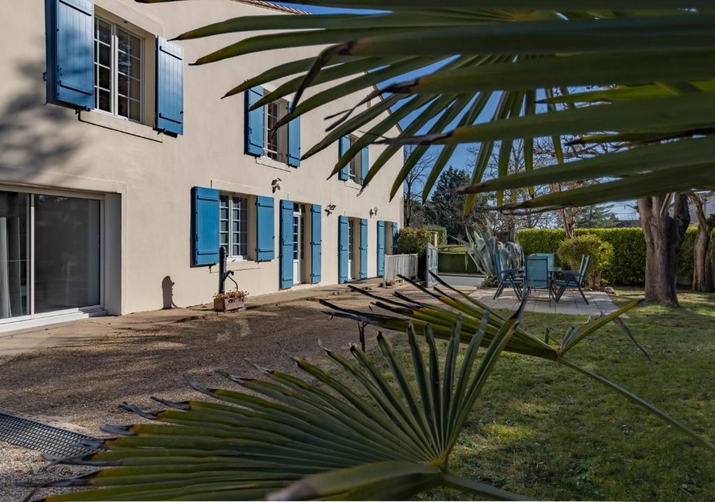 una casa con ventanas azules y una planta frente a ella en Chambre Les Deux Chênes près de Bergerac, en Le Fleix