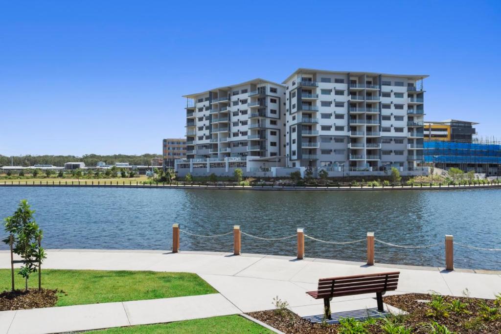 a park bench in front of a large apartment building at Salt at Oceanside in Kawana Waters
