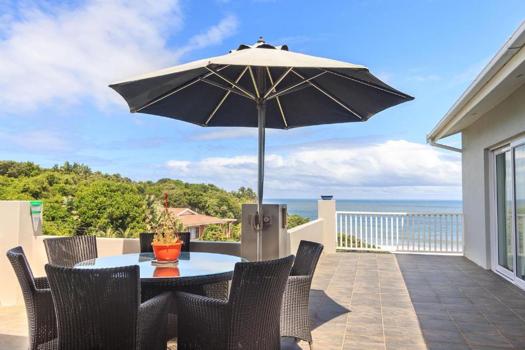 un tavolo e sedie con ombrellone su un balcone di Cherry on Top a Morgan's Bay