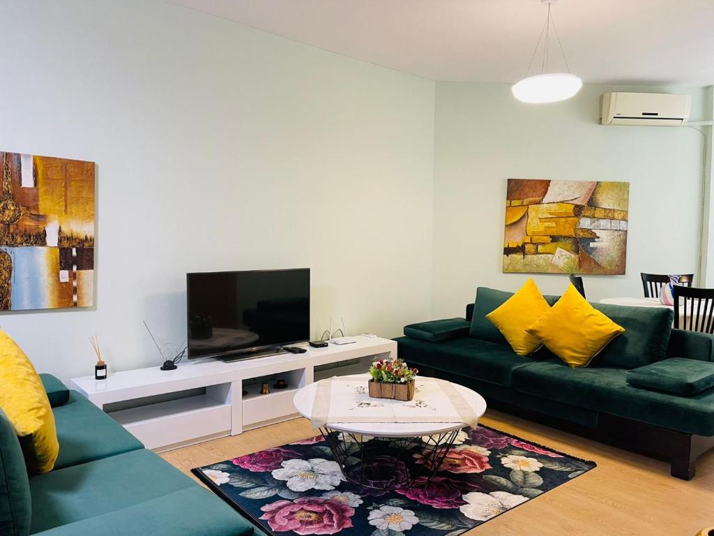 uma sala de estar com dois sofás verdes e uma televisão em New Apartment in Center of Tirana em Tirana