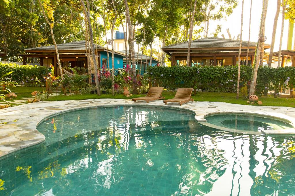 een zwembad met twee stoelen en een huis bij Vila Marina in Arraial d'Ajuda