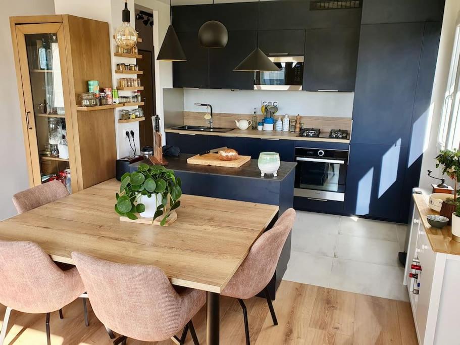 a kitchen with a wooden table and some chairs at Appartement moderne et spacieux (Île de Nantes, futur CHU) in Nantes