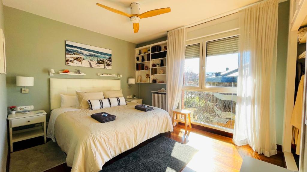 Schlafzimmer mit einem Bett, einem Deckenventilator und einem Fenster in der Unterkunft Casa Carlini Homestay in Getxo