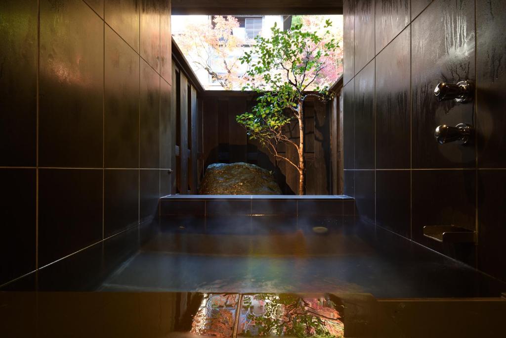 a bathroom with a tub with a reflection of a tree at Oni no Sumika in Izu